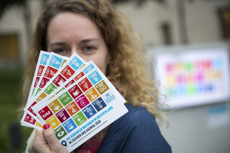 Woman holding cards showing the 17 Sustainable Development Goals (SDGs)