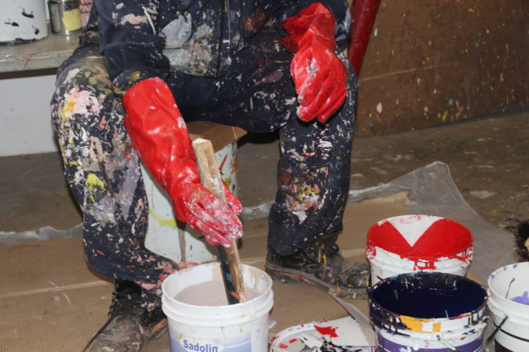 Worker mixing paint while wearing gloves