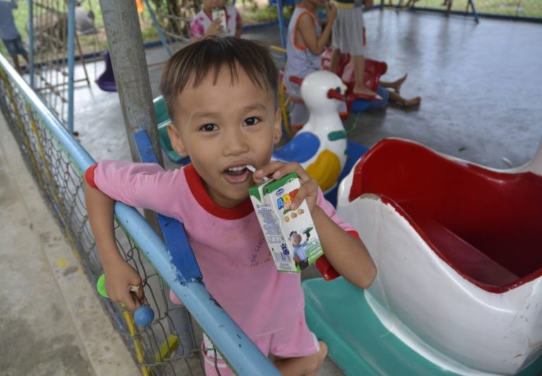 A boy in a playground is drinking from a juice box