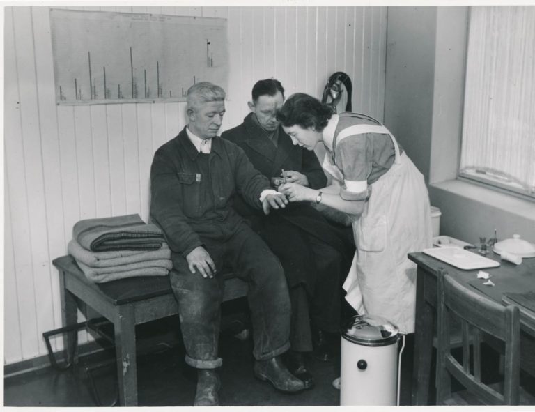 An occupational nurse taking care of a worker who has cut himself