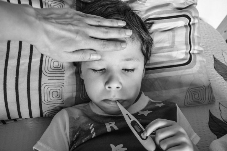 black and white image of a child with a thermometer in mouth