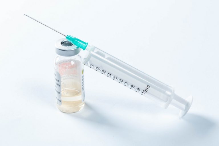 Image of syringe resting on medicine bottle