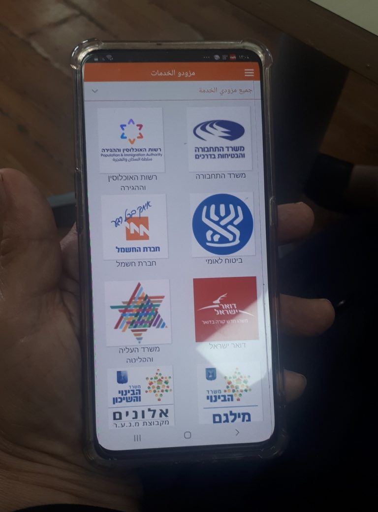 Close up of hand holding smartphone, which shows different apps in Hebrew