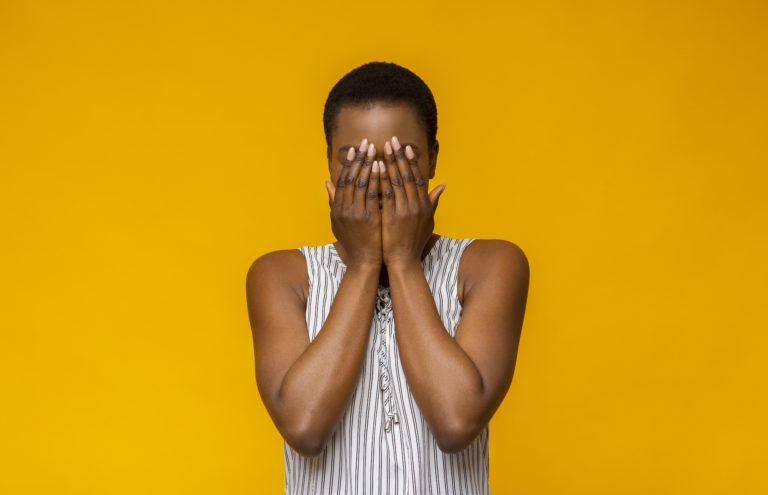 A woman holding her hands over her face