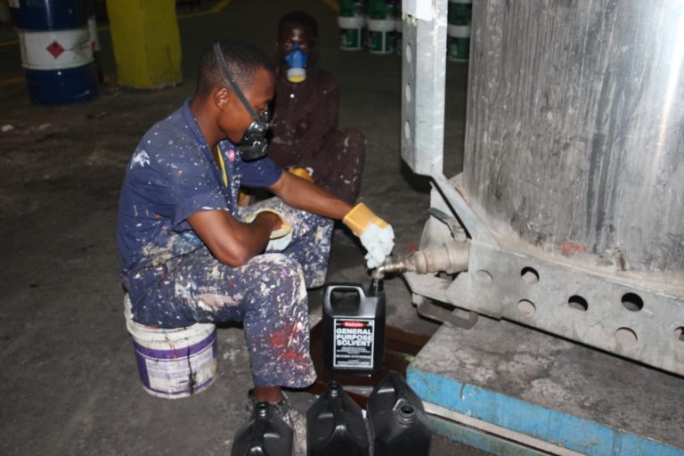 Worker tapping oil from barrel on to a bottle