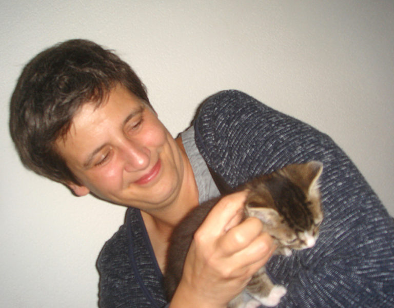 A photograph of Esther Schelling playing with a kitten