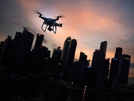Photograph of a drone flying in the foreground and a city skyline in the background