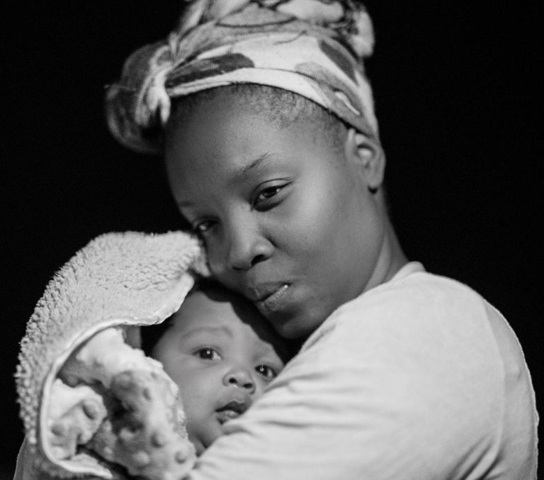 Photo of a black woman cradling a baby