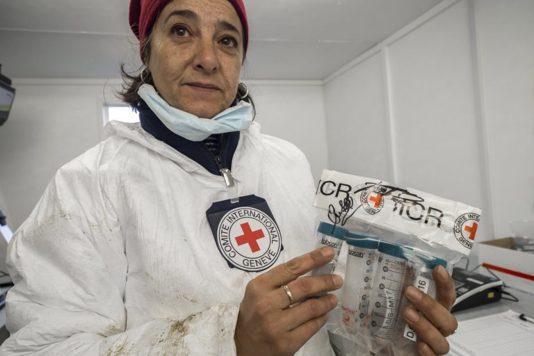 A scientist holds up samples of DNA in a labelled back that will be sent of for processing