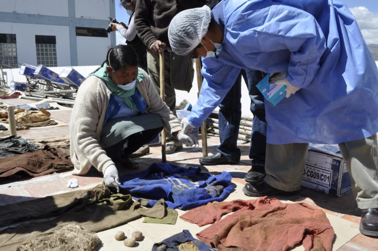 Family members sort through clothes that are laid out on the floor in an attempt to recognise those that may belong to a family member who is missing