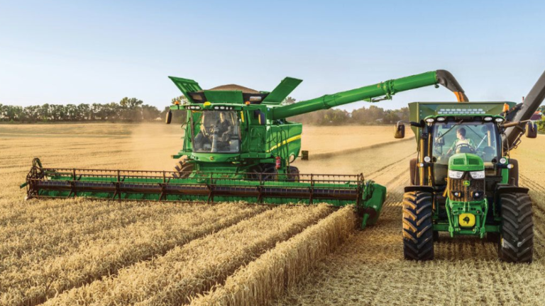 Combine harvester funneling harvested crops into a tractor as it works through the field