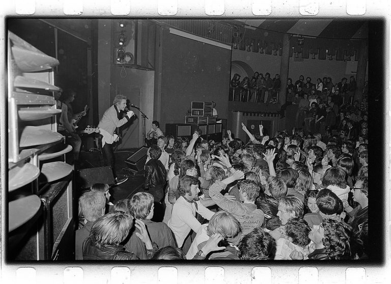 black & white photo showing sex pistols on stage and fans