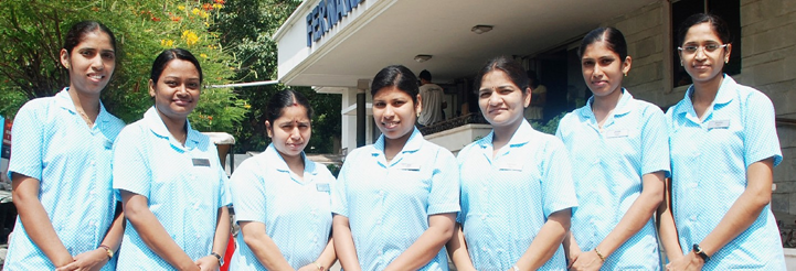 Seven Professional Midwifery Education and Training graduates standing in front of a clinic