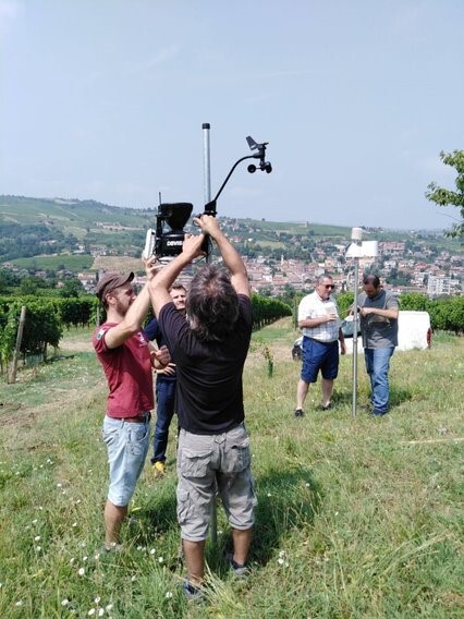 Photo of 5 men involved in setting up two different instruments in a field overlooking a city