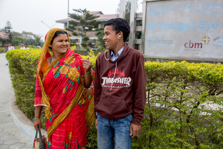 Mother and son looking at each other and smiling in Nepal. The son has just been fitted with a hearing aid