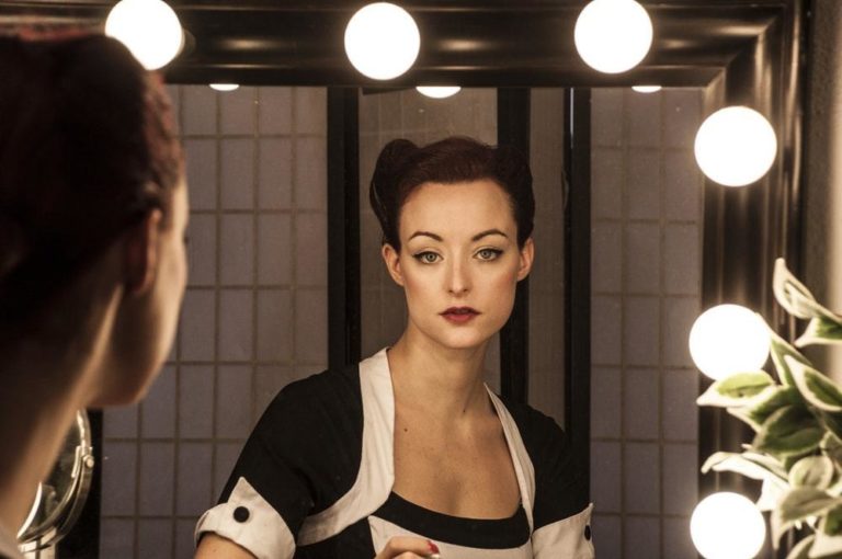 colour photo of the refelction of a woman in a dressing room mirror