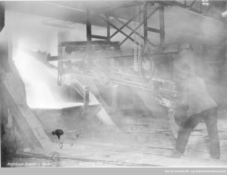 A worker is tapping a carbide furnace in a Norwegian smelter, dating from around 1925