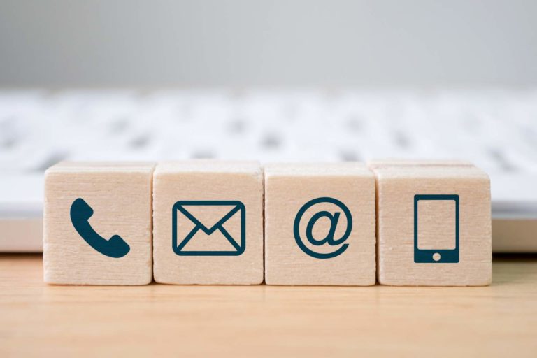 Wooden blocks with technological symbols on them, like a phone, an email and an @ sign.