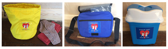 Left: Yellow bucket storage bag with a draw string top. It has the Bishesta logo on the front. The logo is Bishesta is striding into the foreground, smiling, with her arms held high. Perana stands behind Bishesta and proudly watches at her. A reusable menstrual pad and a soft cloth is laid next to the yellow bucket storage bag. Middle: Blue messenger shoulder bag, with the Bishesta logo underneath the flap. A clear plastic bag is fitted into the top of the shoulder bag. Right: a small flip top, yellow and white plastic bin.