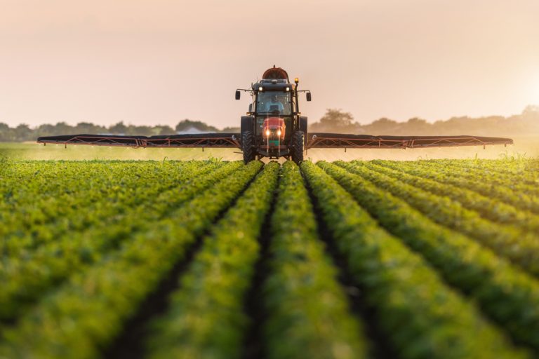 a tractor moving through a crop spraying several rows to either side