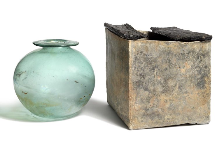 photo of a narrow-necked pale green glass spherical bottle and a rectangular shaped lead box