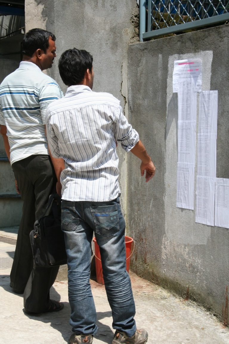 Picture showing Nepalese men looking at job advertisements.