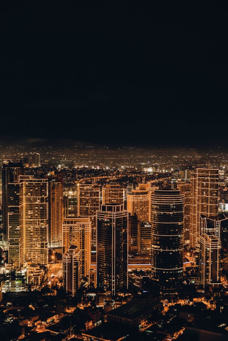 Photograph of a city skyline at night illuminated by skyscrapers and road network