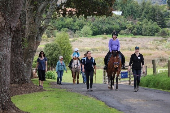 A group of trainers showing people with disabilities how to ride a horse