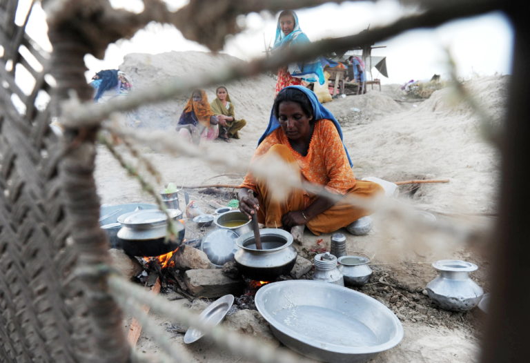 Photograph of a Pakistani woman displaced by floods preparing food for her family on higher ground in Khairpur Nathan Shah in southern Sindh province on September 6, 2010. 