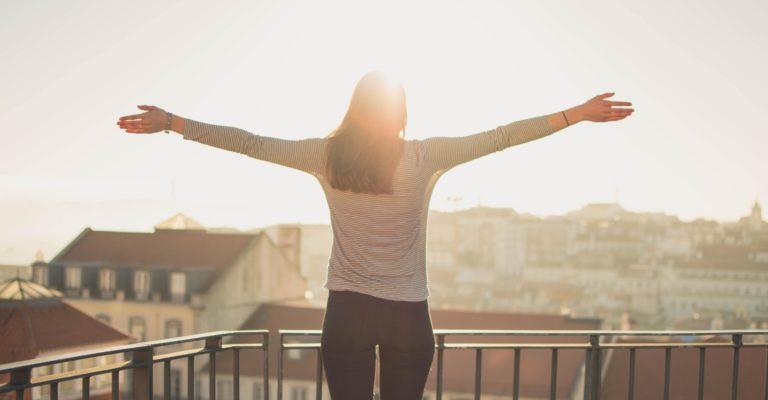 A woman facing the sun with her arms open.