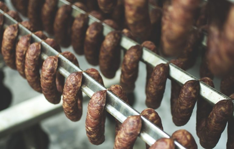 sausages hanging on a metal rack in a smokery