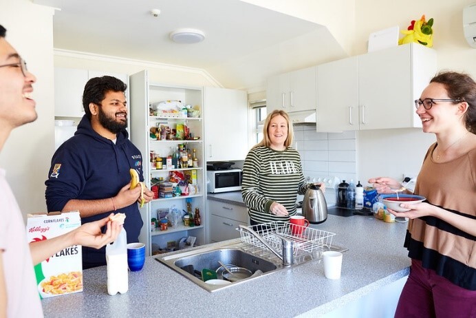 A group of adults chatting around a kitchen table