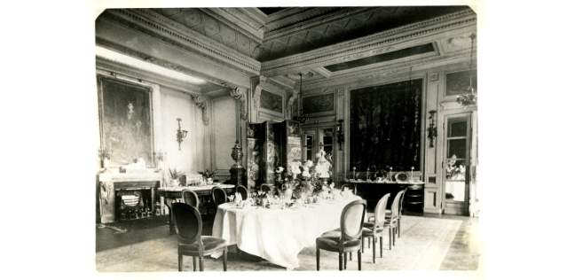 Black and white photograph of an ornate dining room from the late 19th century