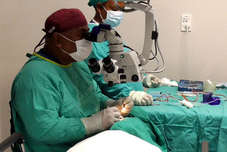 Cataract surgeon operating as the nurse stands by