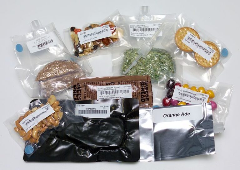 A selection of shrink wrapped dried food for taking into Space, such as crackers, cheese spread, candy coated peanuts, 'orange ade'