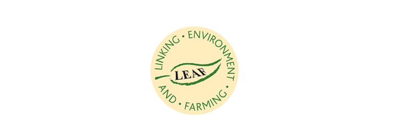 LEAF logo is a cream circle with a green leaf in the middle, and the words LEAF written in black in the middle of the leaf. Around the circle the words Linking Environment And Farming in green font
