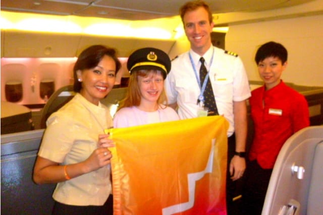 Dana poses with the FutureLearn flag and Cathay Pacific crew on her recent flight to Thailand