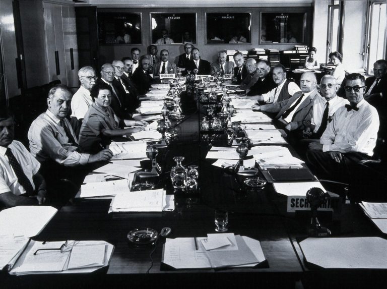 Black and white photograph of a group of people at a meeting in the 1960s