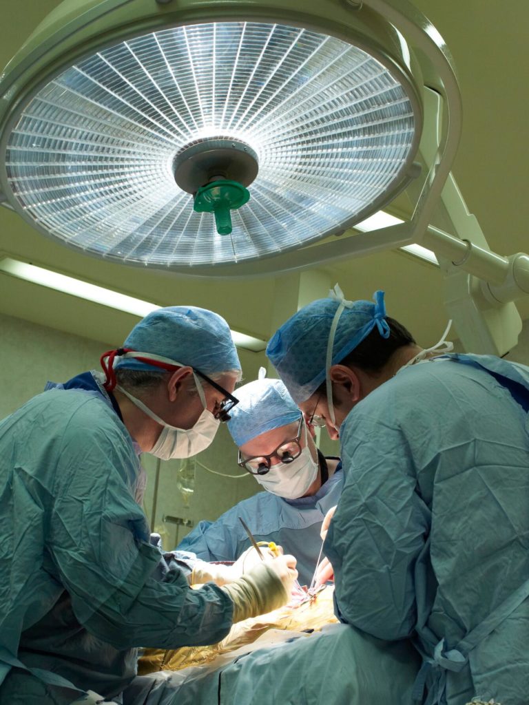 Photograph of three male surgeons operating on a patient