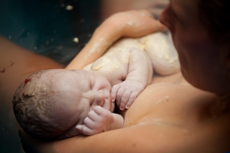 Newborn baby in mother's arm right after birth