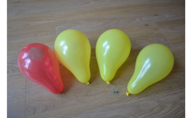 Photo of 4 balloons - one red with tape on it, and 3 yellow. Photo from bacterial resistance activity instructions.