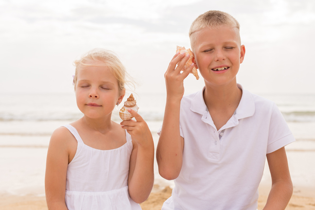 Brother and sister holding a seashell.