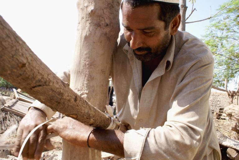 Photograph of a Lunda village resident, starting to rebuild using local materials after the 2010 flood.