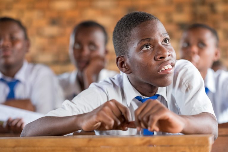 A teenage boy with cerebral palsy sitting at his desk in school