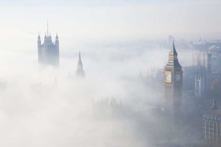 Photograph of London from above with the tops of Big Ben and Westminster poking out through shallow fog