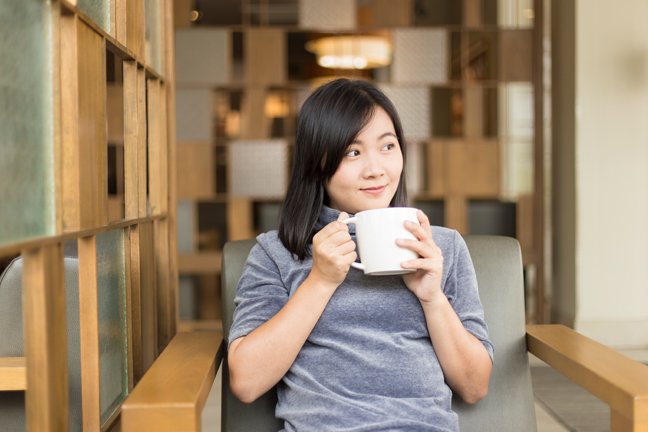 Woman drinking coffee in the morning at a cafe.