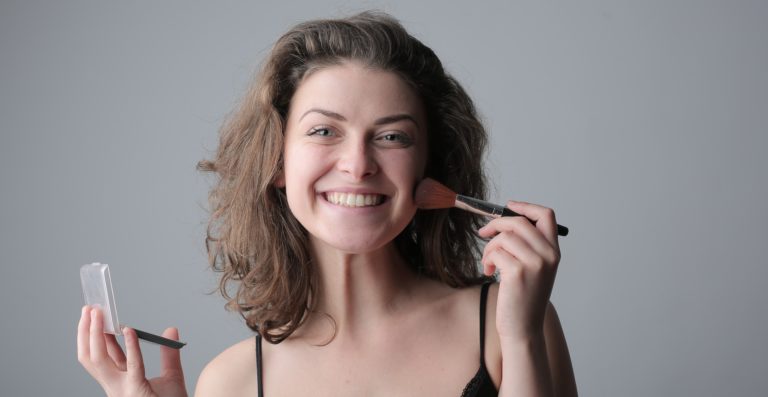 Woman using make-up brush, smiling