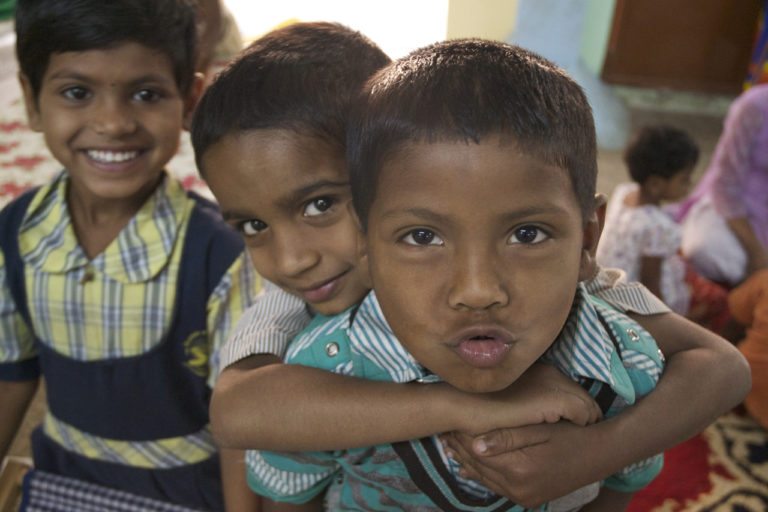 Three friends together. One boy is leaning on the other as he pulls a funny face for the camera