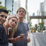 Three teenagers standing on the street smiling.