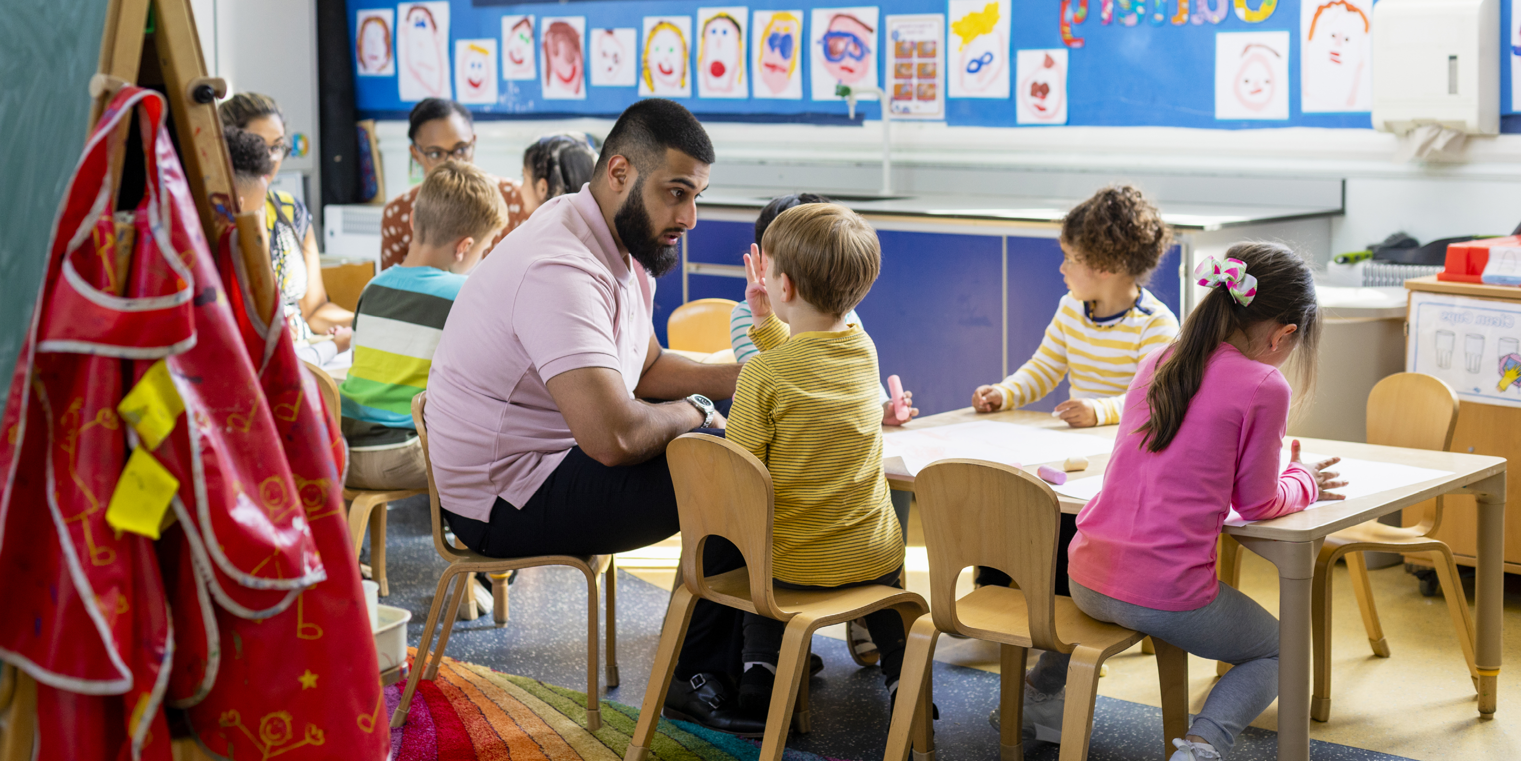 EYFS teacher works with young children in the classroom